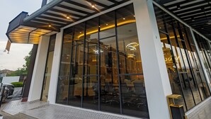 Un edificio moderno con grandes ventanales, un acceso cubierto y un piso inferior de baldosas.