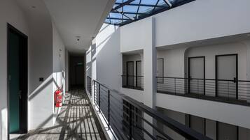 Un interior moderno con techo de vidrio, un extintor y un pasillo que lleva a varias puertas.