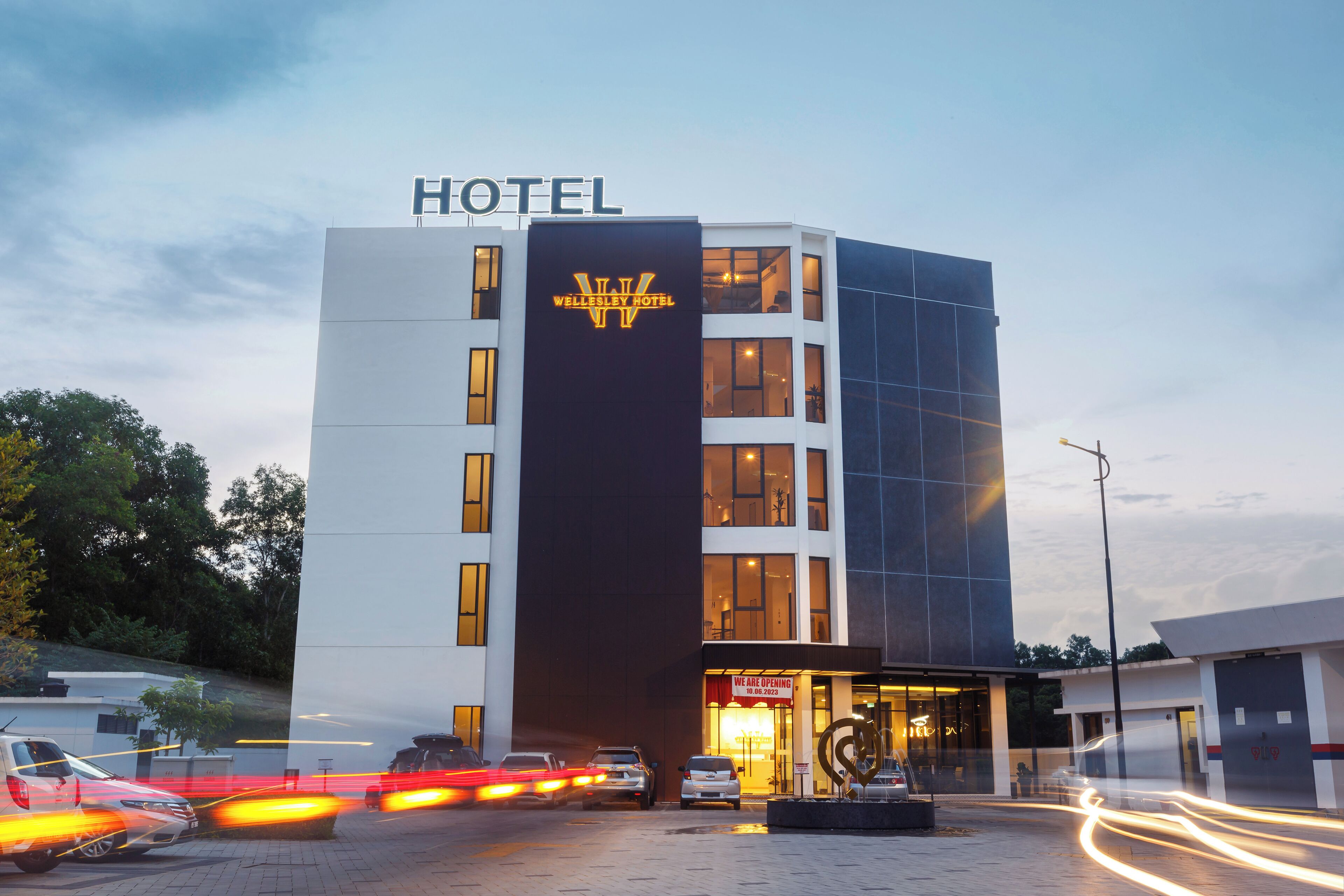 Een hotel met een modern design, herkenbaar aan een opvallend bord en een ruime entree.