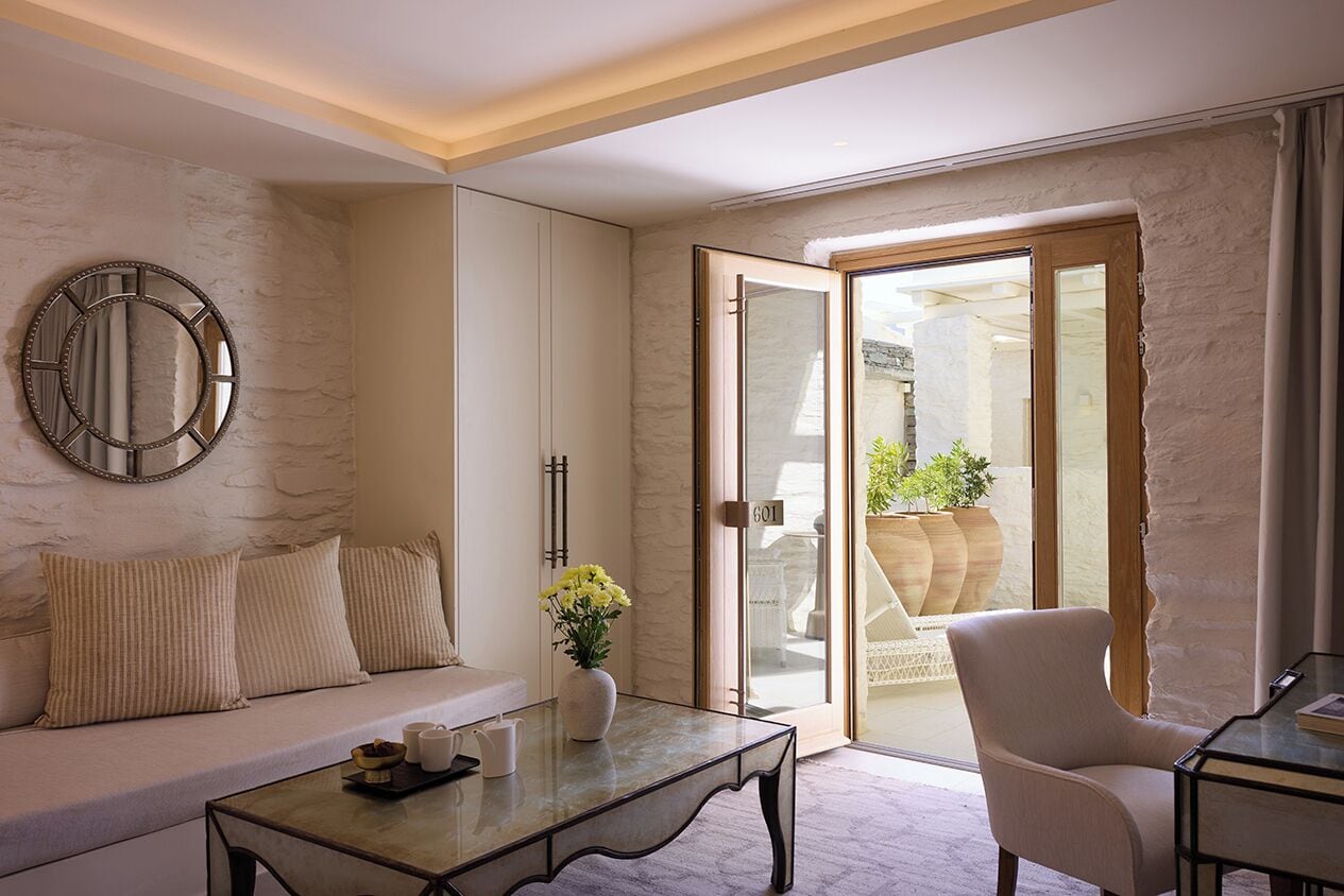A modern living room with a sofa, a coffee table, a chair, and a large mirror on the wall.