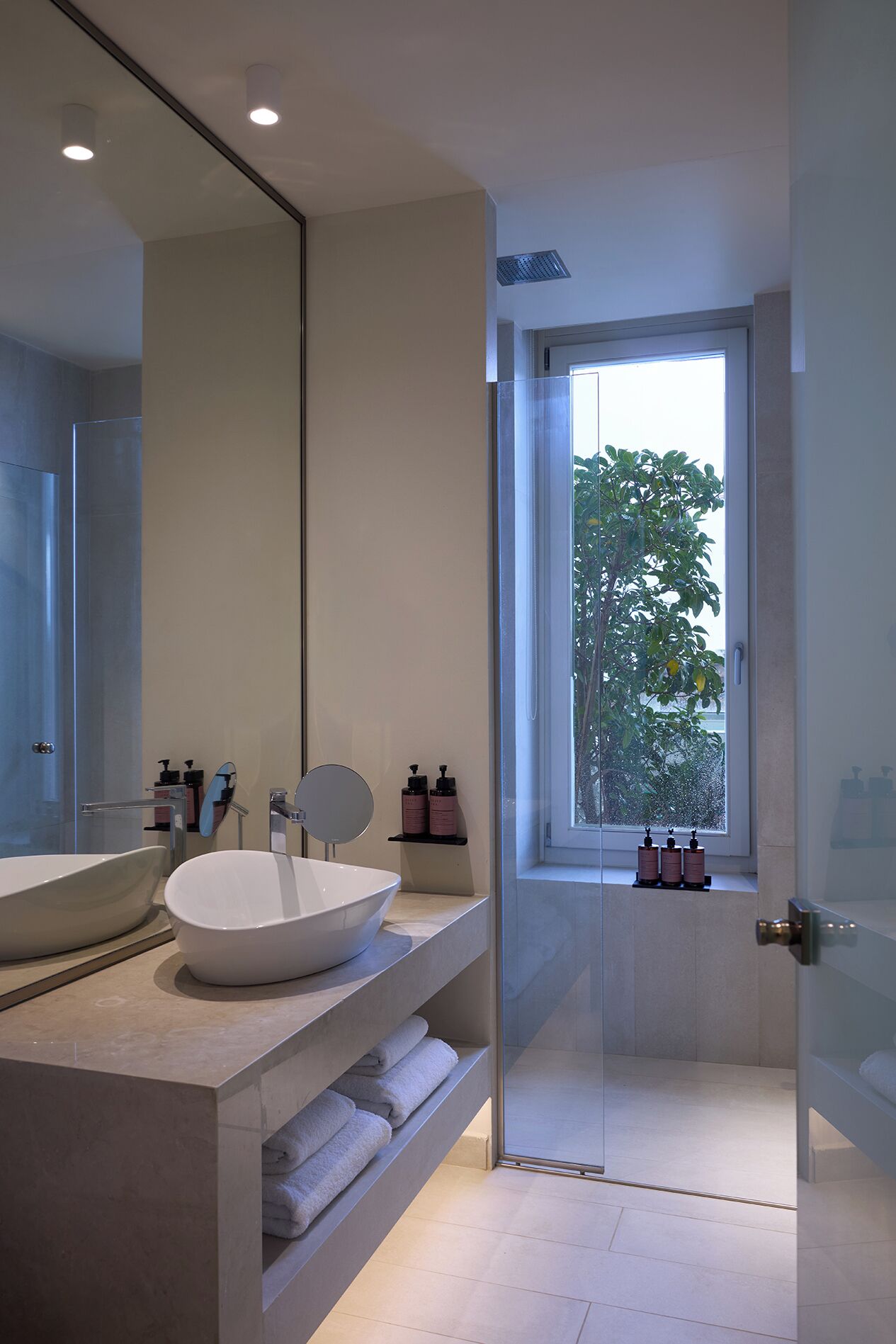 A modern bathroom with a large mirror, a white sink, and a shower area.