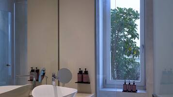 A modern bathroom with a large mirror, a white sink, and a shower area.