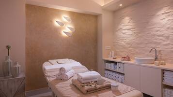 Relax in a serene spa room with a massage table, vanity, and textured wall.