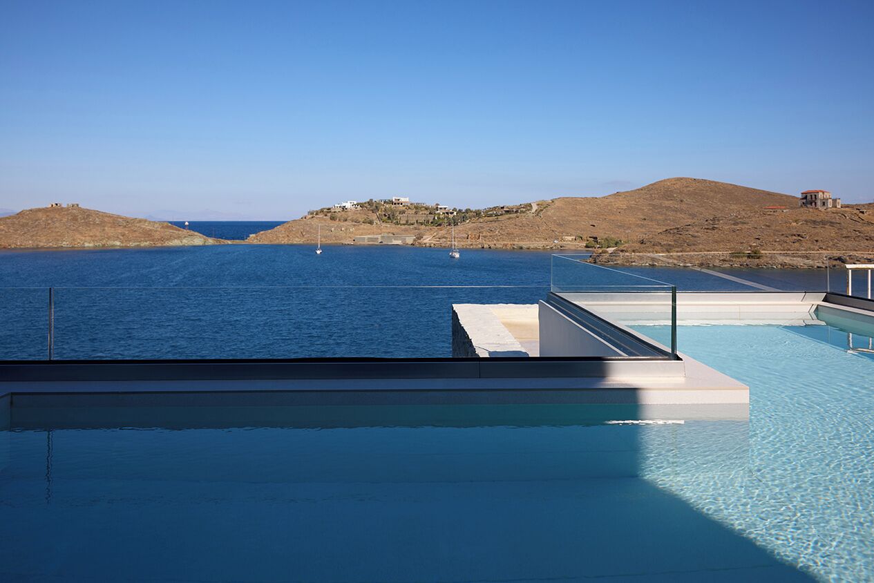Una piscina infinita con vistas despejadas al mar y colinas lejanas.