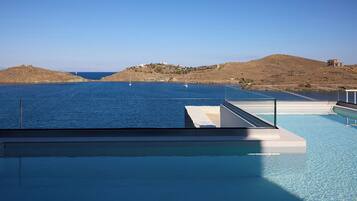 Una piscina infinita con vistas despejadas al mar y colinas lejanas.