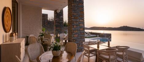 A terrace with wicker furniture, a round table with a potted plant, and a stone wall.
