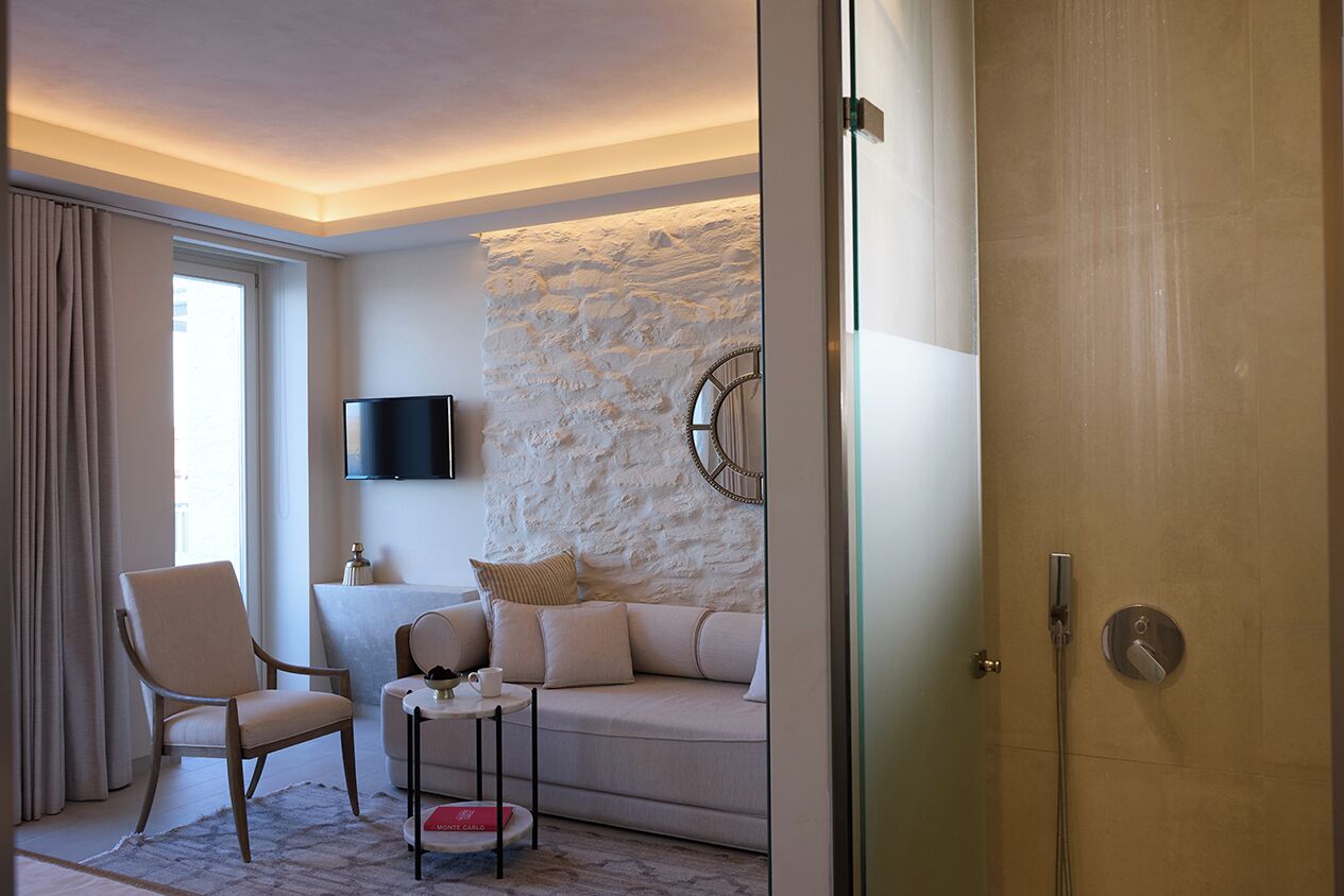 Una sala de estar moderna con una pared de acento de piedra, un televisor de pantalla plana, un sofá, una silla y una mesa de centro.