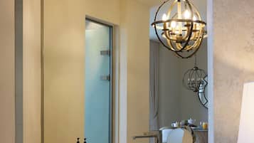 A modern bathroom with a large mirror, a round sink, and a chandelier.