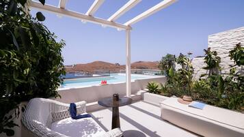 A terrace with a white pergola, a pool, and a view of the sea.