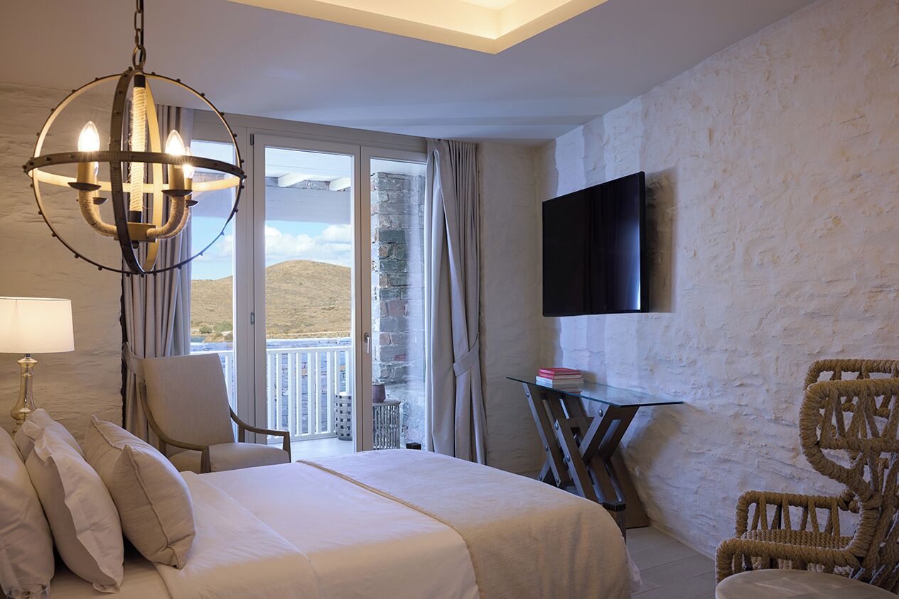 A hotel room with a bed, a chandelier, a television, a chair, and a table.