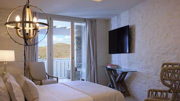 A hotel room with a bed, a chandelier, a television, a chair, and a table.