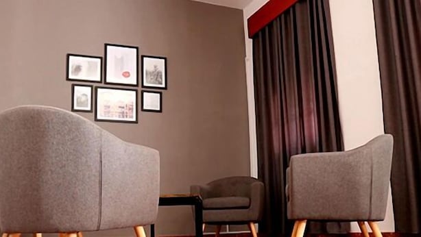 A room with two grey armchairs, a small table, and a wall with framed pictures. - Hostal Restaurante Asador EL PAISANO (Utrera)