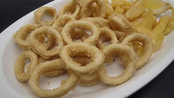 Un plato de aros de calamares fritos y gajos de limón.
