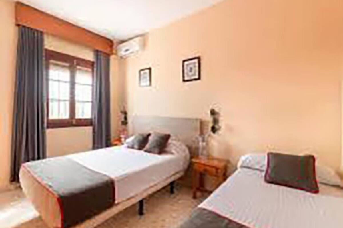 Ein Hotelzimmer mit einem Bett, einem Nachttisch und einem Fenster mit Vorhängen.