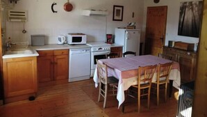 Cuina compacta amb electrodomèstics bàsics, taula de dinar amb cadires i terra de fusta.