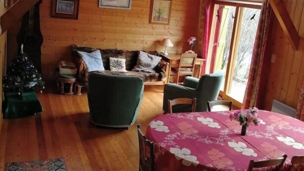 Un interior de fusta acollidor amb una zona de menjador, un sofà i un arbre de Nadal.