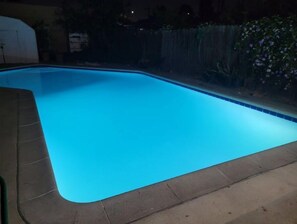 A swimming pool with a tiled edge and a dark surrounding area.