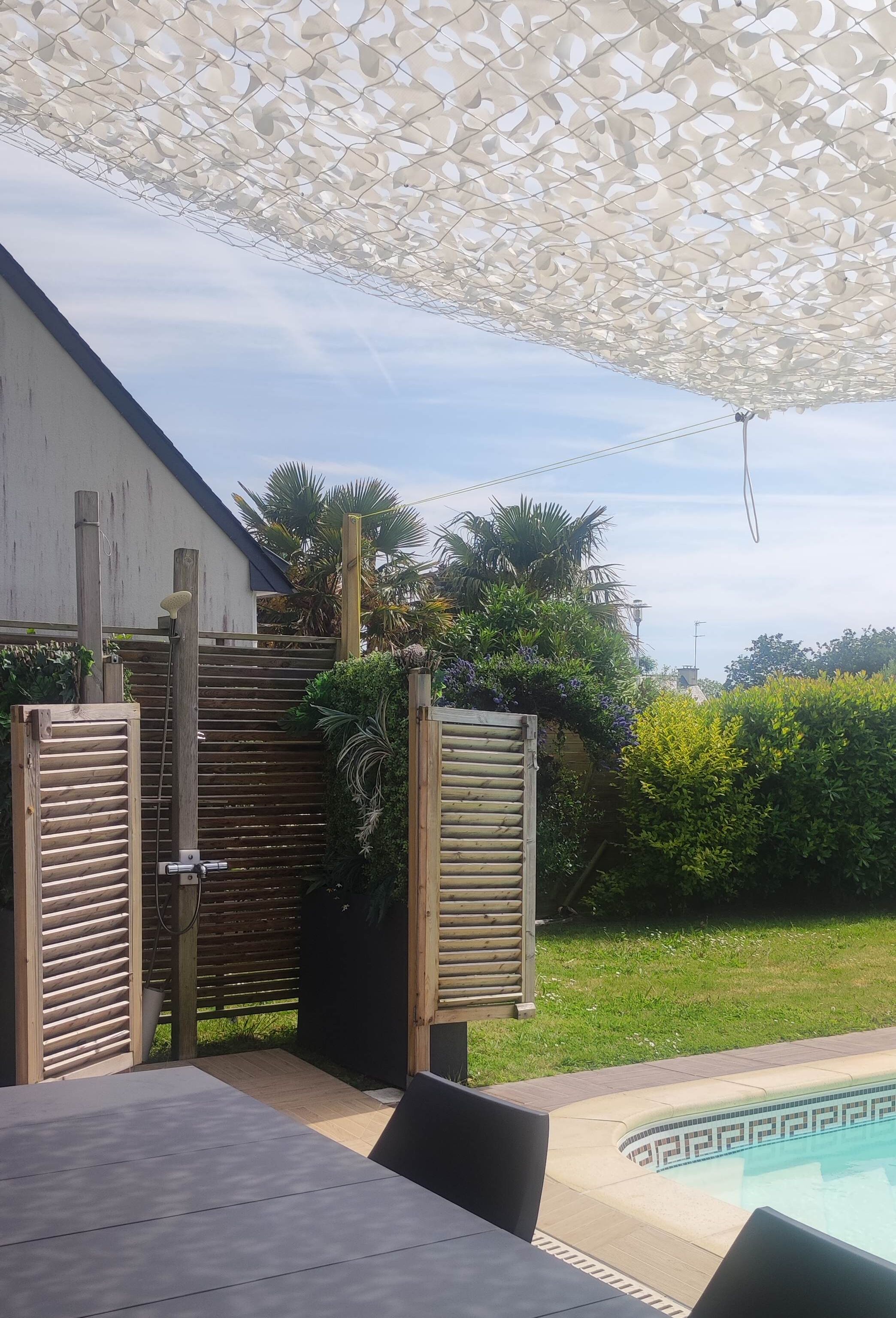 A poolside area with a pergola, wooden gates, and a table.