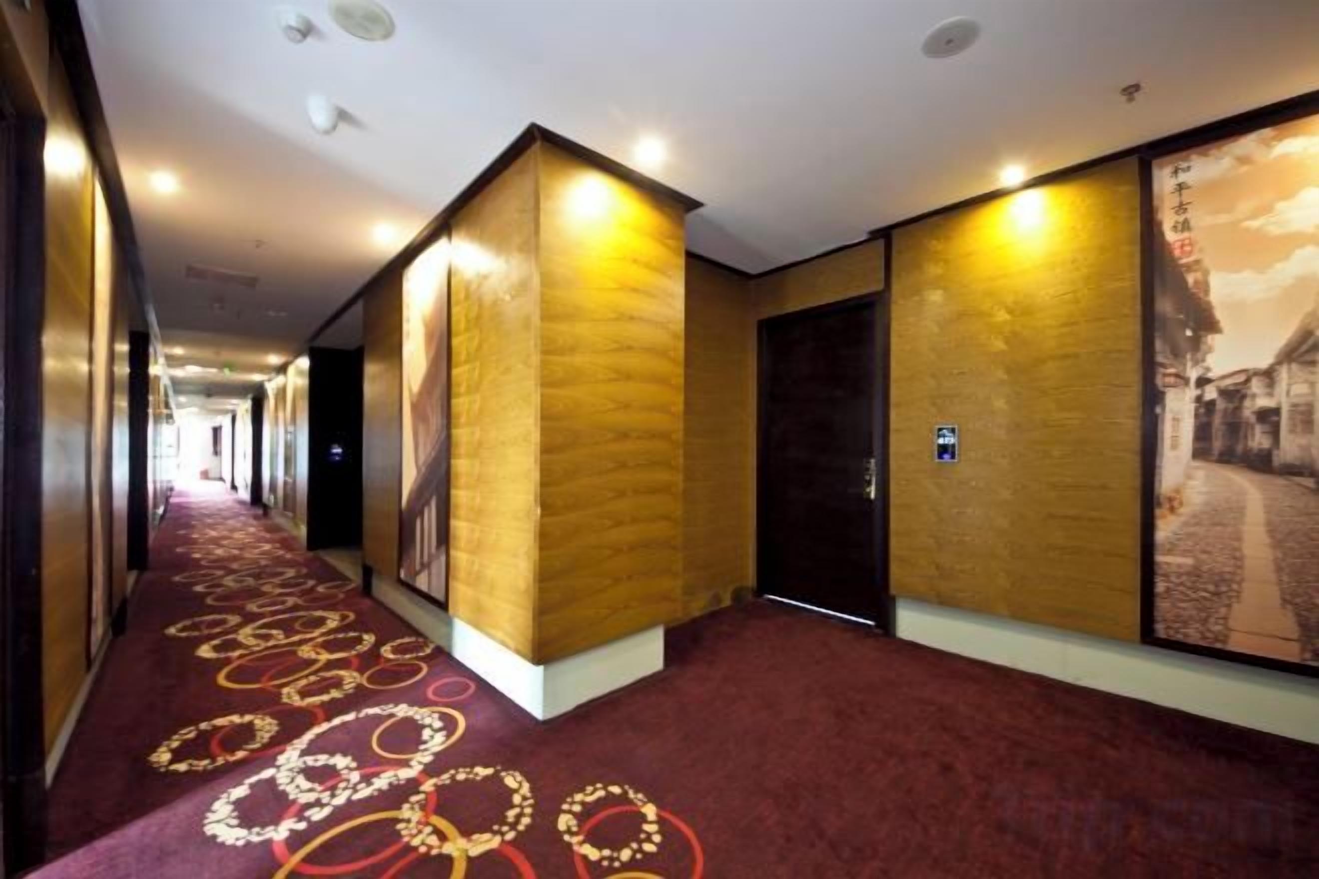 A hotel corridor with a red carpet, walls with a textured pattern, and a door with a sign.