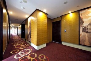 Un pasillo de hotel con alfombra roja, paredes con un diseño texturizado y una puerta con un letrero.