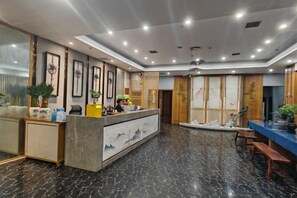 Un hall d’hôtel comprenant un comptoir d’accueil, un espace salon et une grande fenêtre.