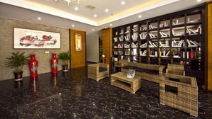 A lobby with a marble floor, wicker furniture, a bookshelf, and decorative vases.