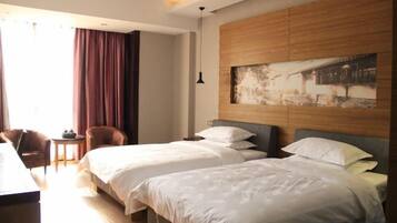 A hotel room with two beds, a desk, and a chair.