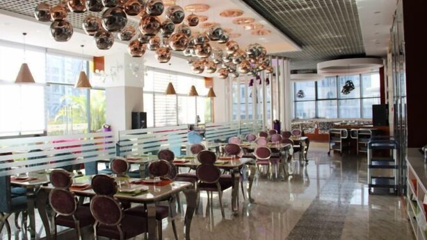 A spacious restaurant with high ceilings, hanging spherical light fixtures, and a long counter with seating.
