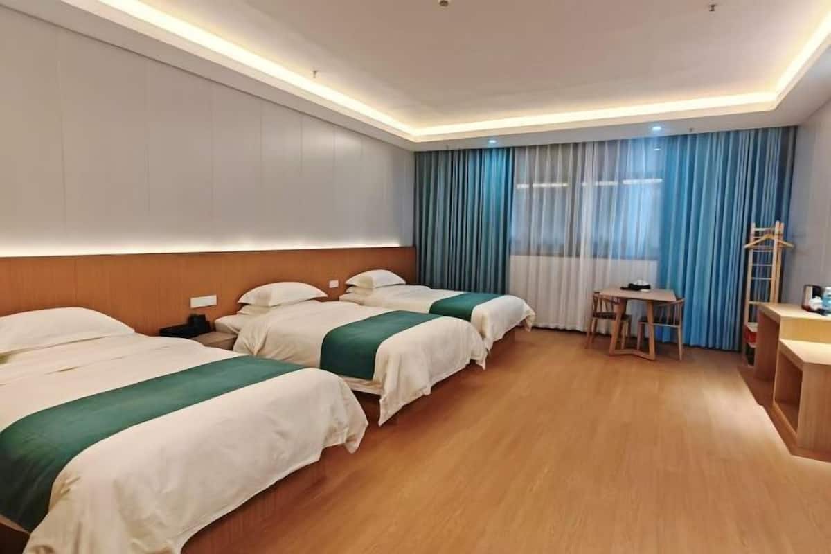 Hotellihuone, jossa on kaksi sänkyä, työpöytä, tuoli ja pieni pöytä.