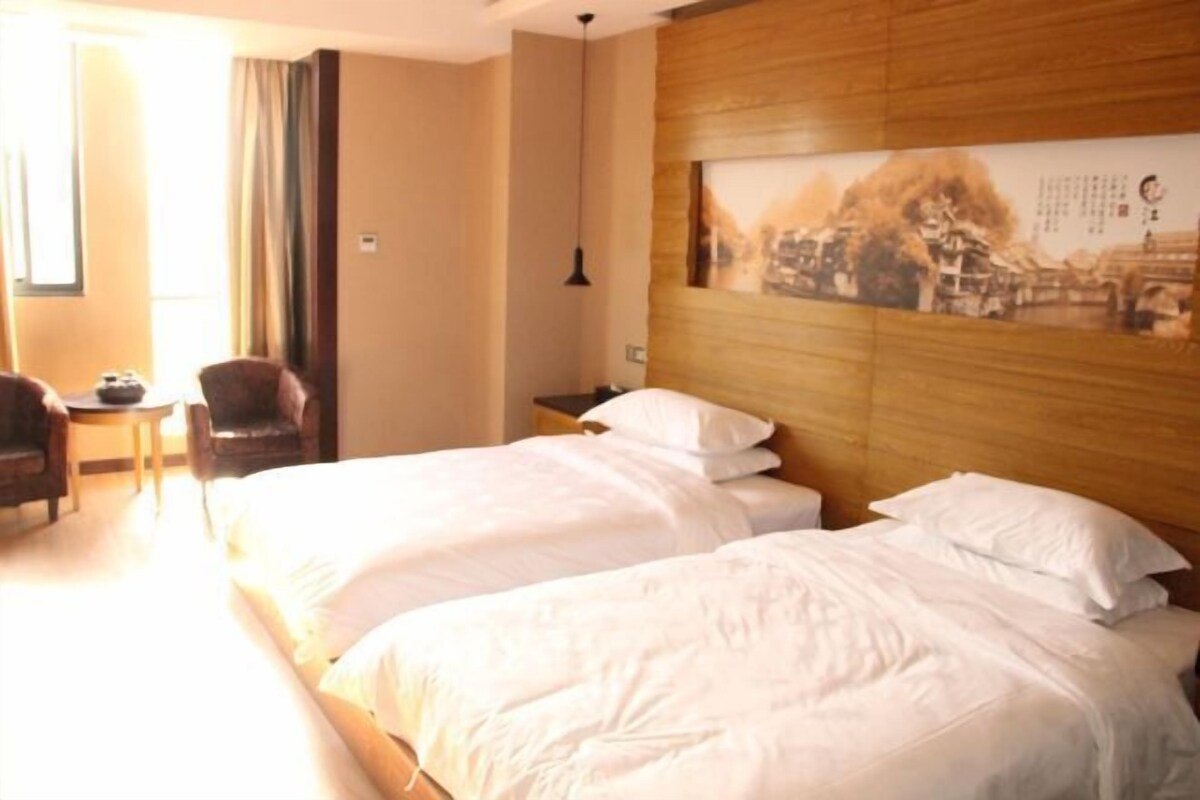 A hotel room with two beds, a wooden headboard, a small table, and a chair.