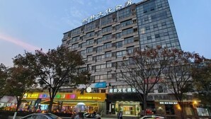 A multi-story hotel with a modern glass facade, located in an urban setting with visible signage for various businesses.