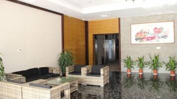A lobby with seating arrangements, a reception desk, and potted plants.