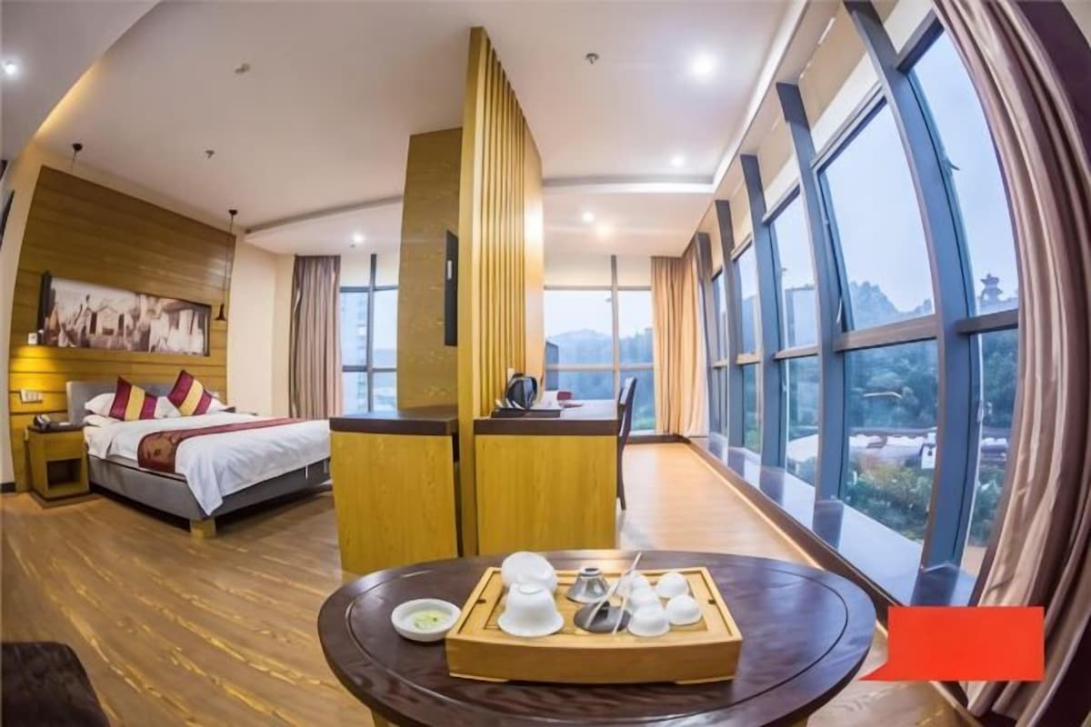 Habitación de hotel con cama, mesita de noche y vistas al exterior.