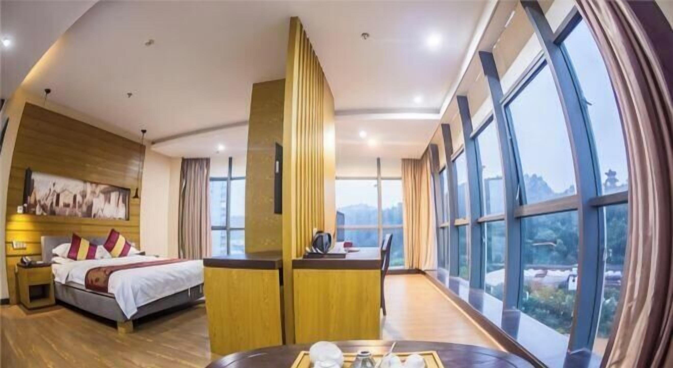 A hotel room with a bed, bedside table, and a view of the outdoors.