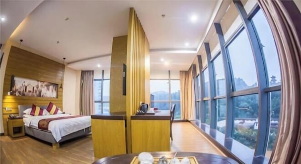 A hotel room with a bed, bedside table, and a view of the outdoors.