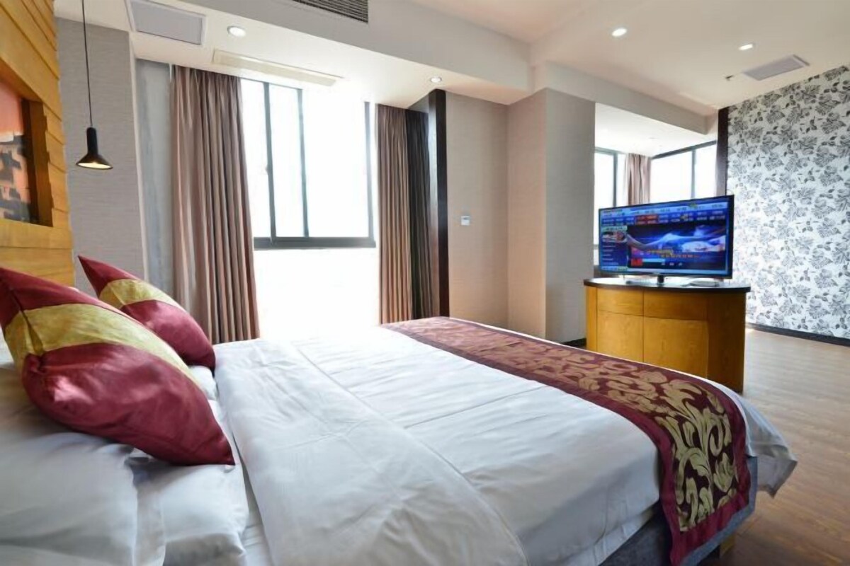 A hotel room with a large bed, a television, and a desk.