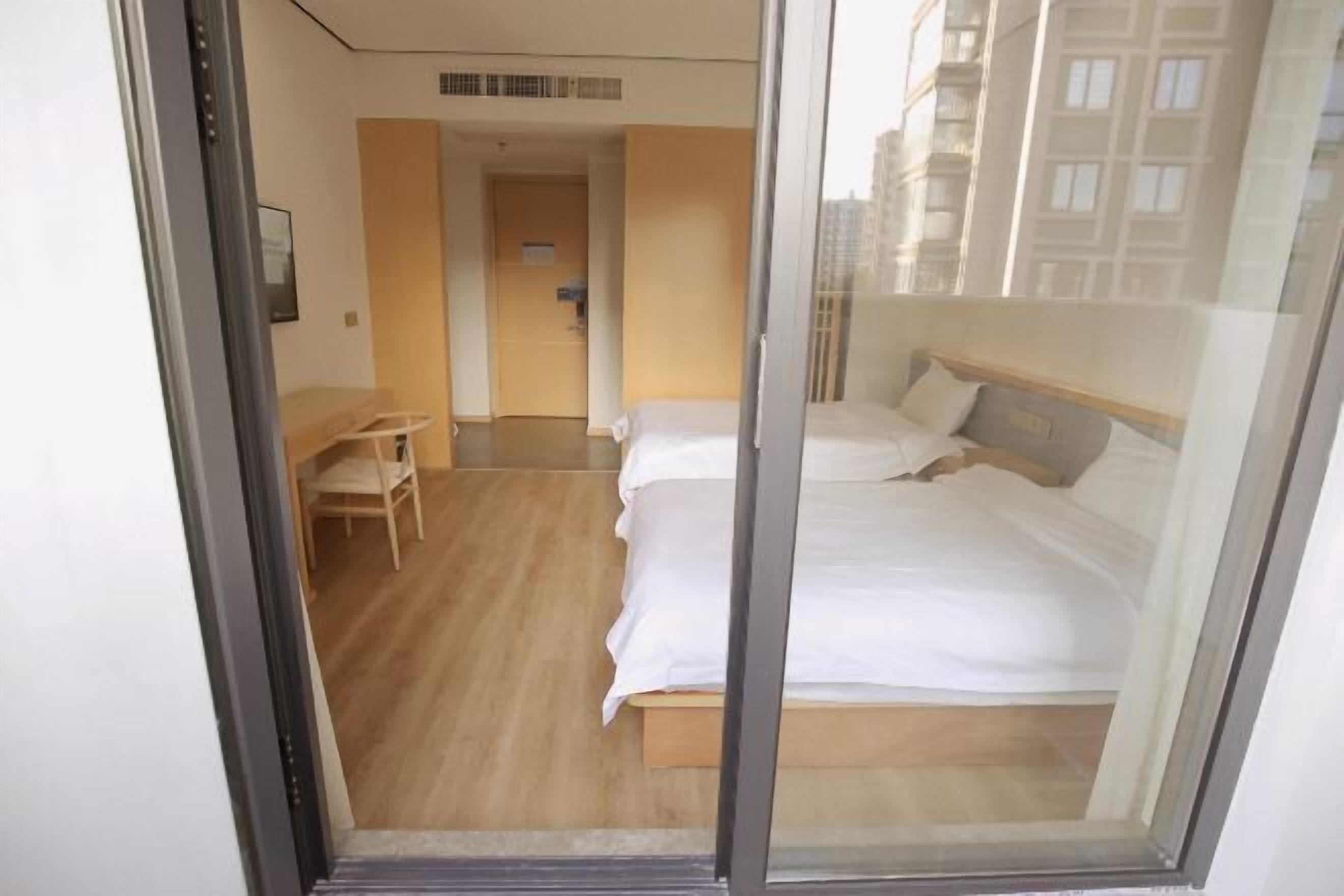 A hotel room with a bed, a desk, and a chair.