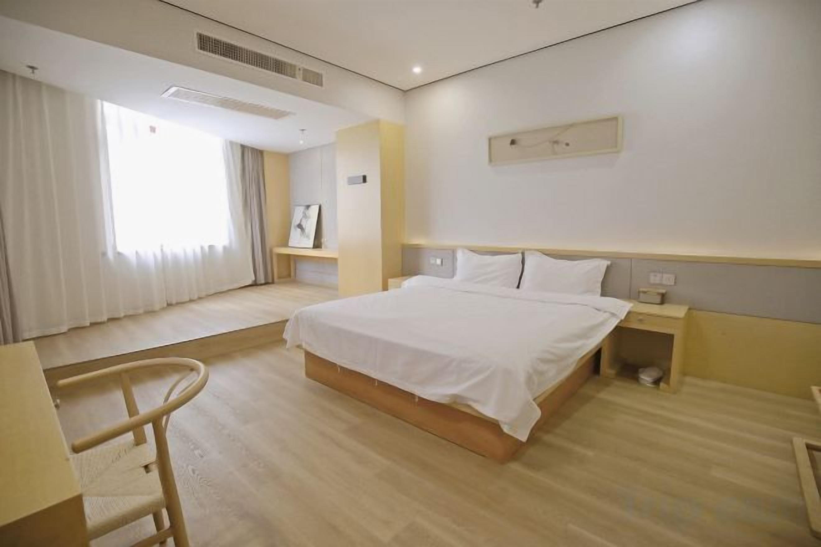 Een hotelkamer met een bed, nachtkastje en een stoel.