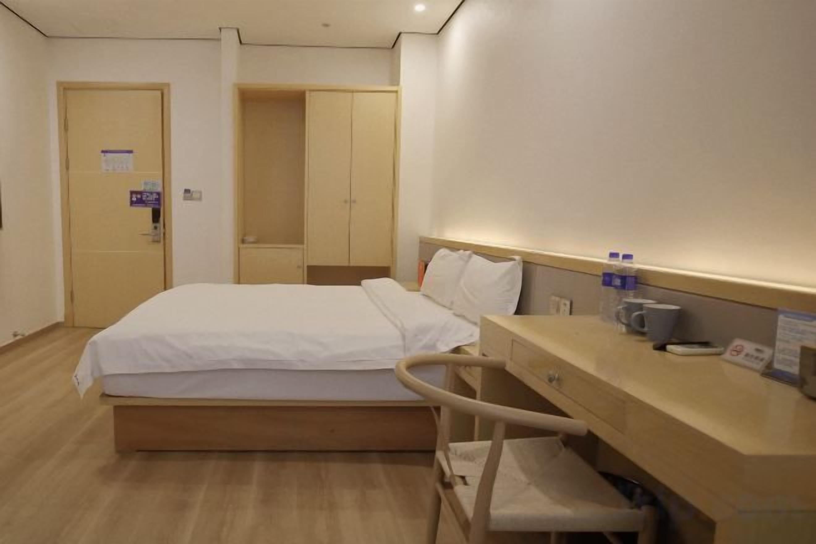 Une chambre d’hôtel avec un lit, un bureau, une chaise et une armoire.
