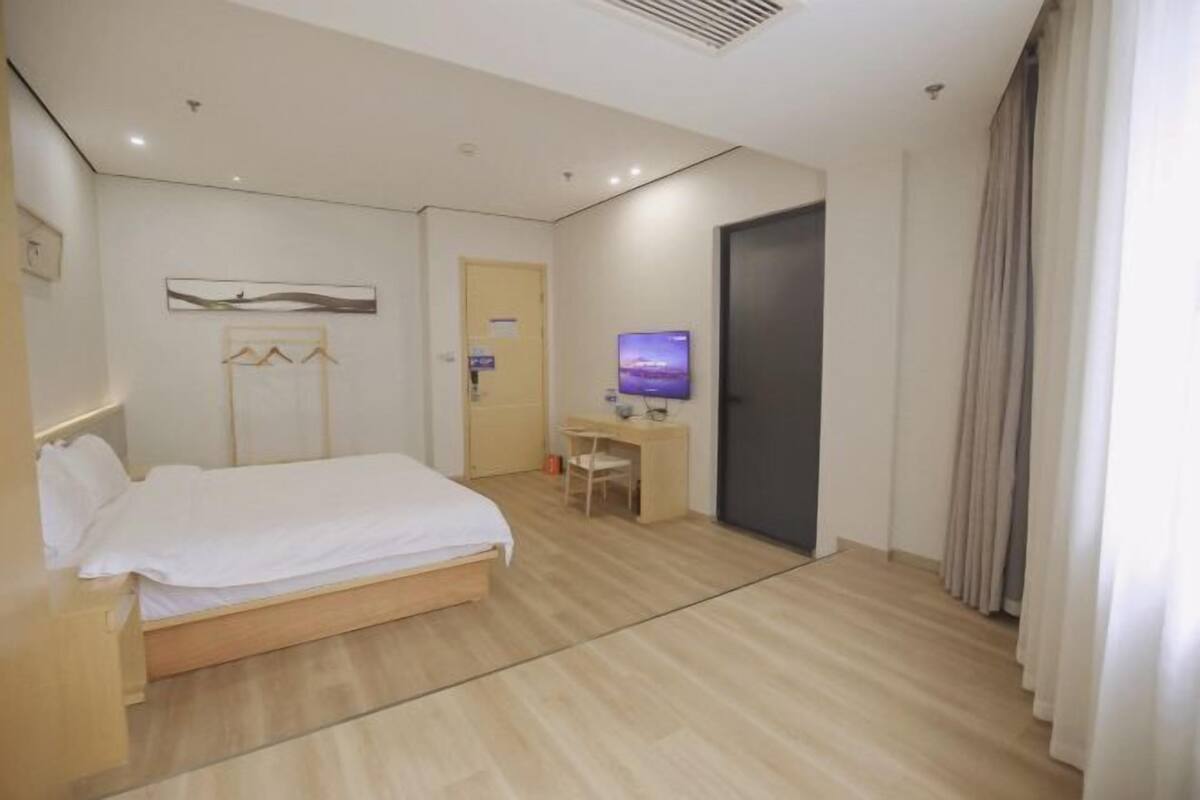 Una habitación de hotel con cama, escritorio, silla, televisor y puerta.