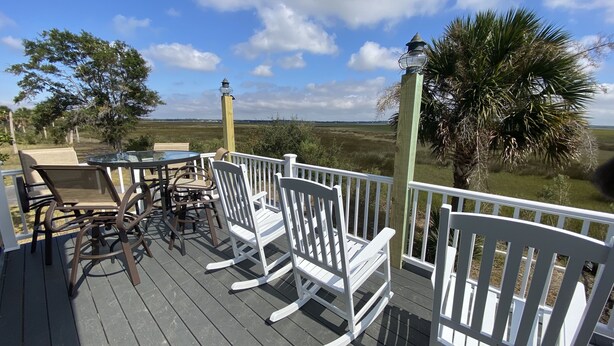Une terrasse en bois avec des rampes blanches, du mobilier d’extérieur et une vue sur le paysage.