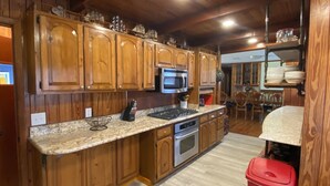 Une cuisine dotée de meubles en bois, d’un four à micro-ondes, d’une cuisinière et d’un coin repas avec des chaises et une table.