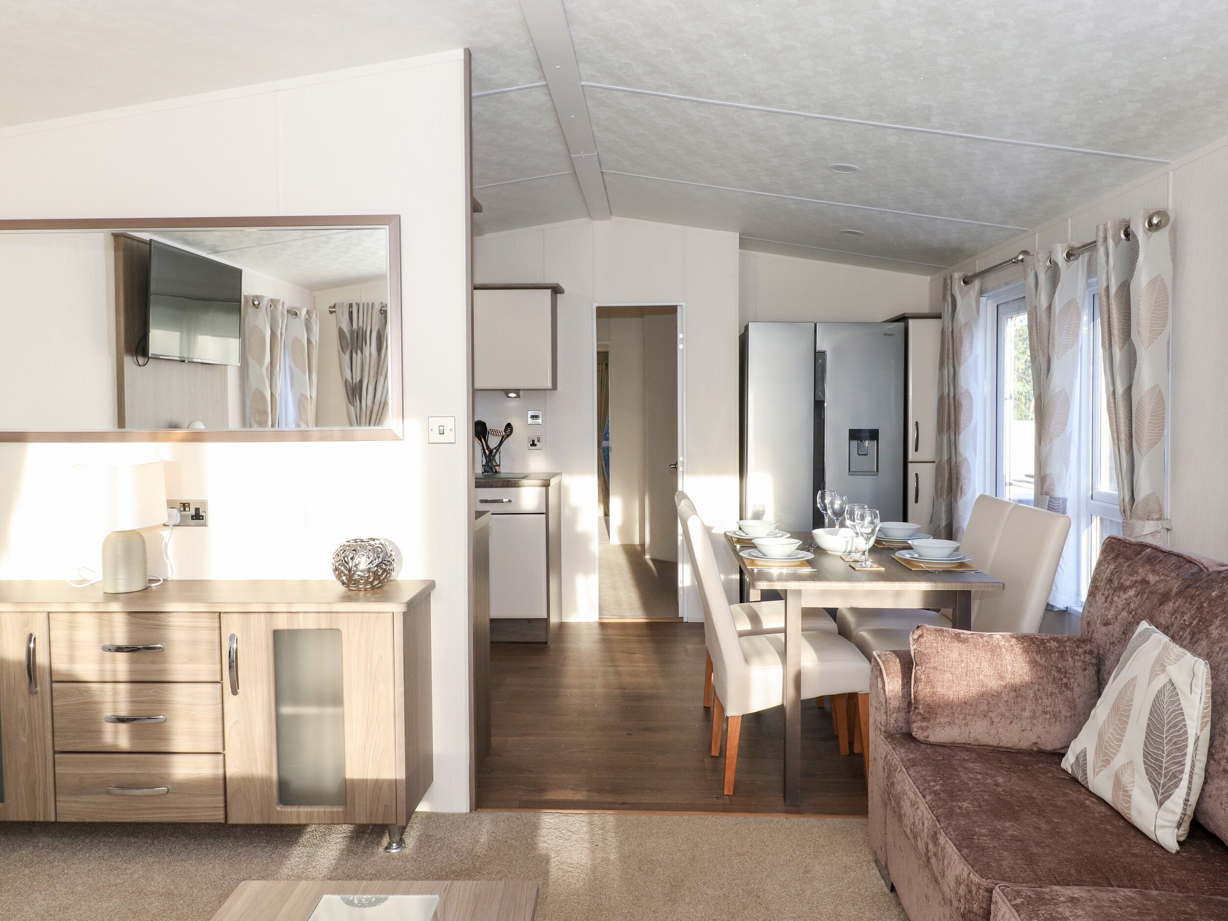 A modern kitchen with a dining area, a sofa, and a mirror.