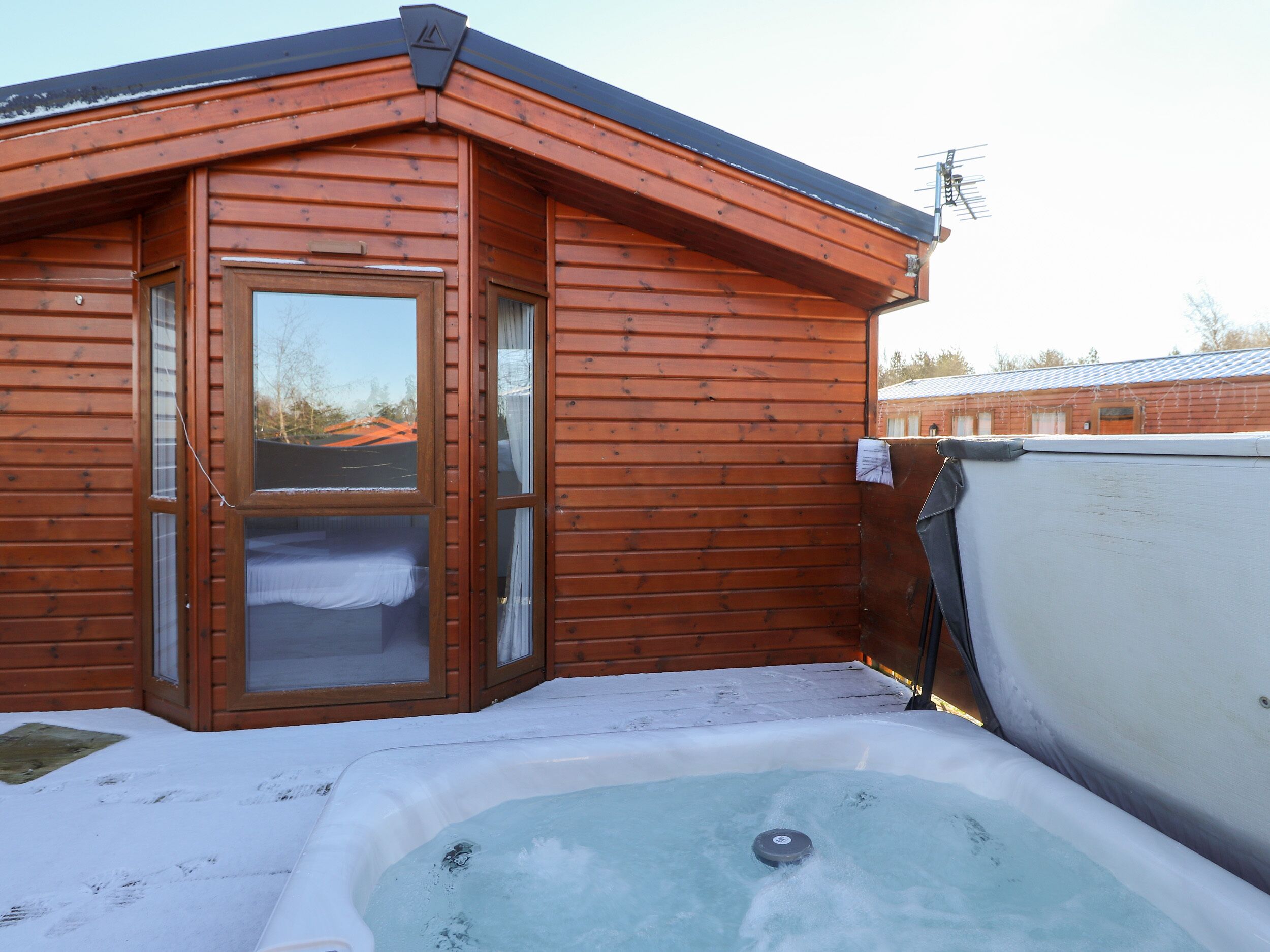 A wooden cabin with a hot tub and a glass door.