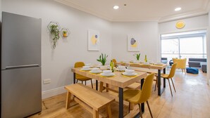 Une cuisine moderne avec des tables en bois et des chaises jaunes, équipée d’un réfrigérateur encastré.