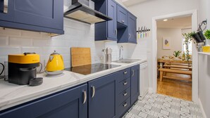 Une cuisine moderne avec des meubles de couleur bleu foncé, un plan de travail blanc et une hotte de cuisine en acier inoxydable.
