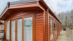 En hytte med træfacade, store vinduer og en terrasse.
