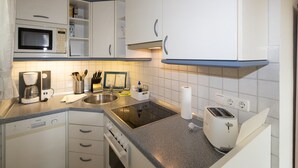 Eine moderne Küche mit weißen Schränken, einer Mikrowelle, einer Kaffeemaschine, einem Toaster und einem Spülbecken.