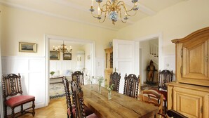 Ein Esszimmer mit Holztisch und -stühlen, einer Kandelaber und einem Schrank.