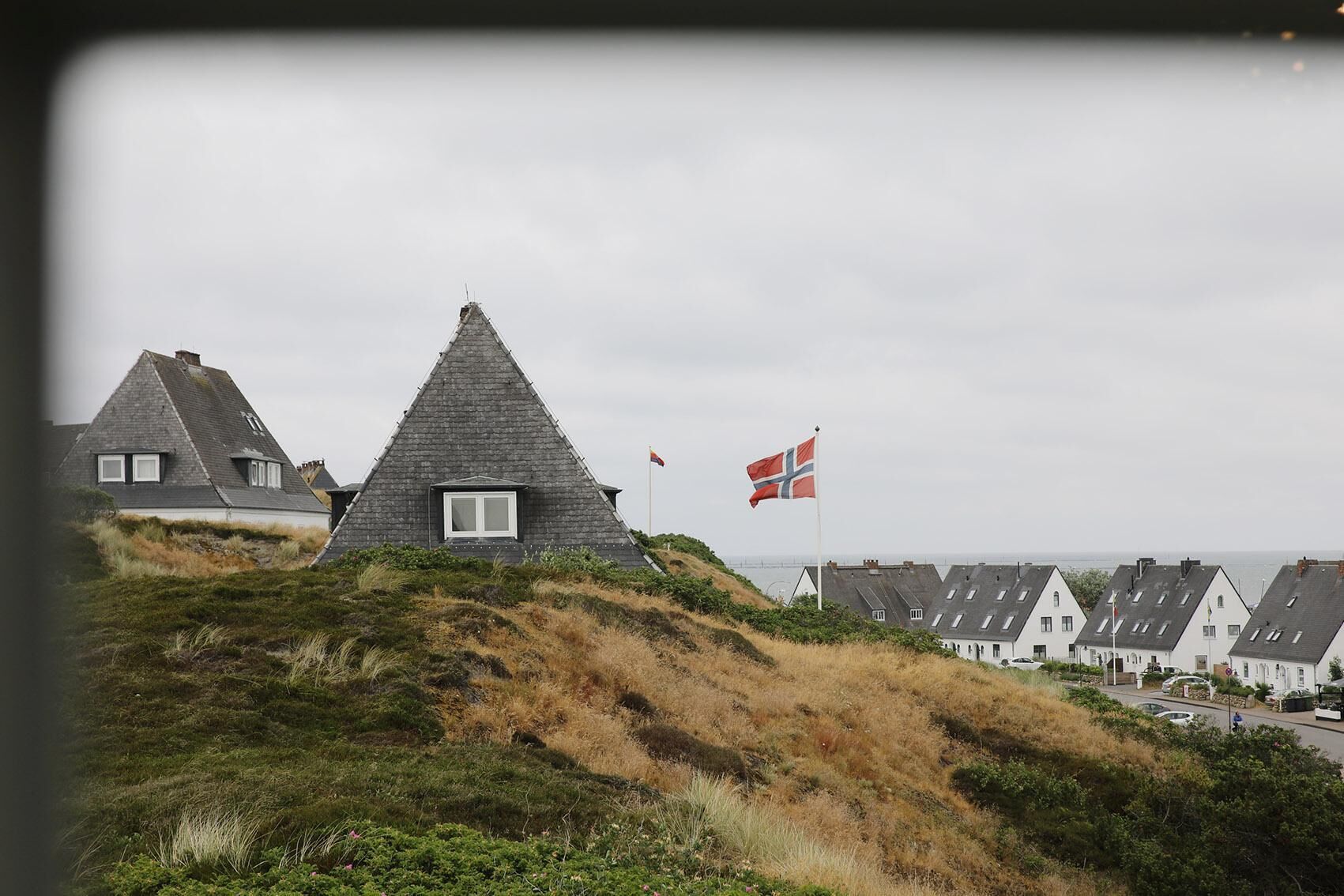 Een kustdorp met traditionele huizen, een vlag en uitzicht op zee.